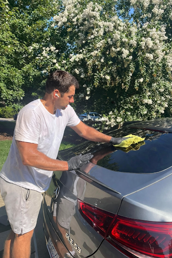 Alex hand-detailing a Mercedes coupe in a driveway